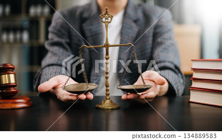 Male lawyer in the office with brass scale on wooden table. justice and law concept in morning light Male lawyer in the office with brass scale on wooden table. justice and law concept in morning light 134889583