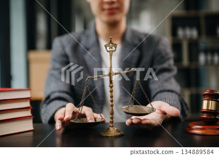 Male lawyer in the office with brass scale on wooden table. justice and law concept in morning light 134889584
