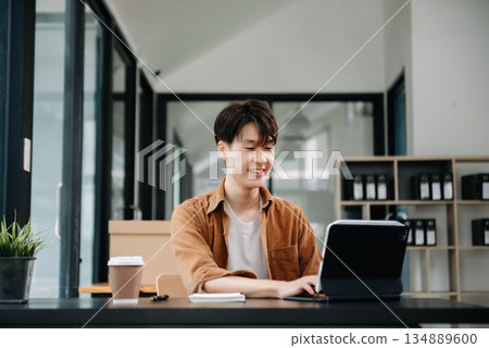 Portrait of a young man sitting at his desk in the office. Portrait of a young man sitting at his desk in the office. 134889600