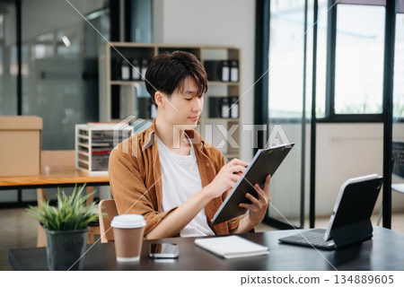 Portrait of a young man sitting at his desk in the office. 134889605