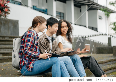Two smart young Asian college students focusing on his school project, looking at laptop and tablet, discussing and working together Two smart young Asian college students focusing on his school project, looking at laptop and tablet, discussing and working together 134889645