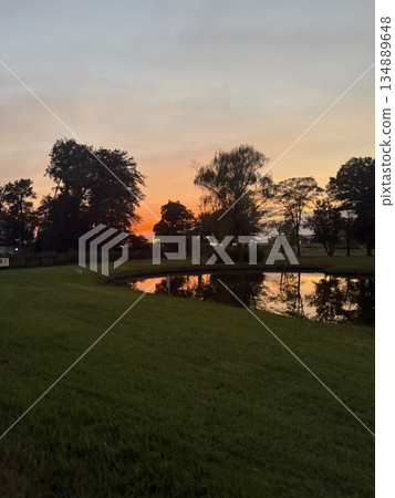 夕陽和樹木倒映在池塘里 夕陽和樹木倒映在池塘里 134889648