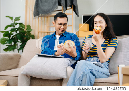Asian young attractive couple man and woman use tablet and smartphone online shopping furniture decorate house with carton package move in new house. Young married moving home. Asian young attractive couple man and woman use tablet and smartphone online shopping furniture decorate house with carton package move in new house. Young married moving home. 134889763