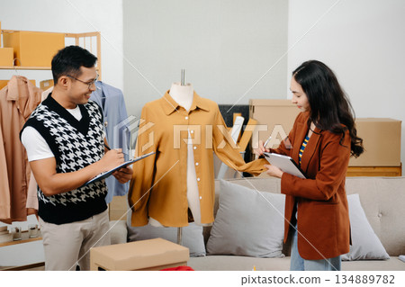Two professional young Asia cheerful lady fashion designer teamwork with casual site on table use tablet meeting discuss final design share idea in shop. 134889782