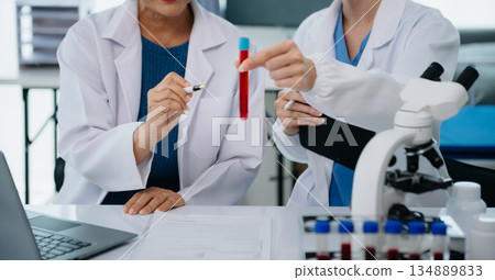 Scientist team meeting and writing analysis results in the laboratory study and analyze scientific sample 134889833