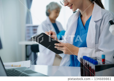 Scientist team meeting and writing analysis results in the laboratory study and analyze scientific sample 134889861