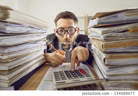 Business man working at the desk in office with a pile of folders and a stack of papers. 134889877