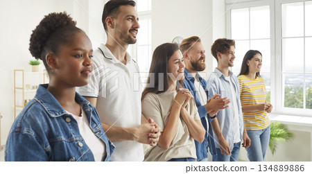 Diverse audience standing in row in office and listening to speech at business seminar Diverse audience standing in row in office and listening to speech at business seminar 134889886