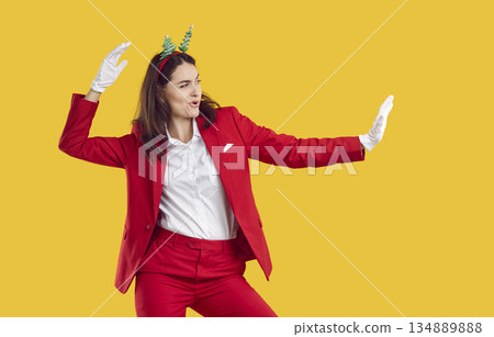 Cool woman in red suit and New Year's accessories is dancing and having fun at New Year's party. Cool woman in red suit and New Year's accessories is dancing and having fun at New Year's party. 134889888