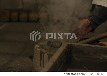 鐵匠將黏土汁液倒在燒紅的鐵塊上。 134890168