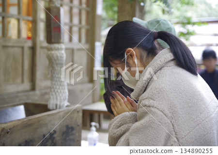 Young woman praying at a shrine 134890255