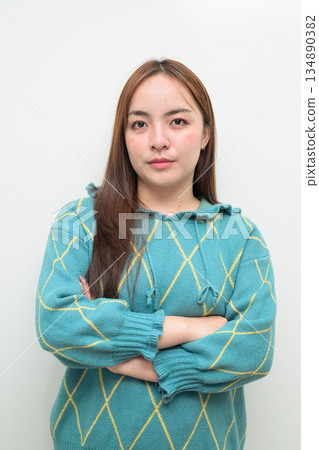 Portrait of a young Asian woman against white background with arms crossed 134890382