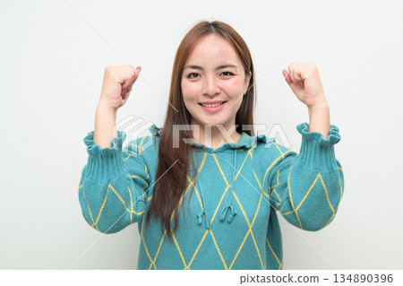 Portrait of a young Asian woman against white background with arm raised Portrait of a young Asian woman against white background with arm raised 134890396