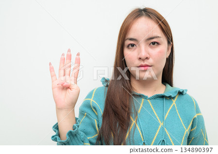 Portrait of a young Asian woman against white background showing number four with fingers 134890397