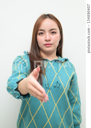 Portrait of a young Asian woman against white background reaching out hand for handshake 134890407