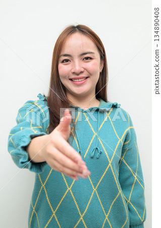 Portrait of a young Asian woman against white background reaching out hand for handshake Portrait of a young Asian woman against white background reaching out hand for handshake 134890408