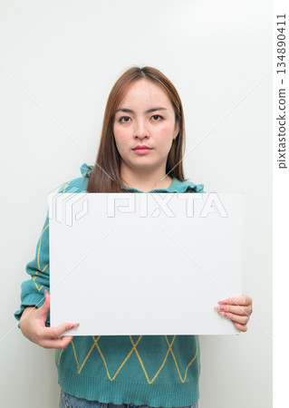 Portrait of a young Asian woman against white background showing copy space placard 134890411