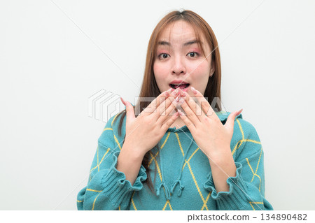 Portrait of a young surprised Asian woman against white background Portrait of a young surprised Asian woman against white background 134890482