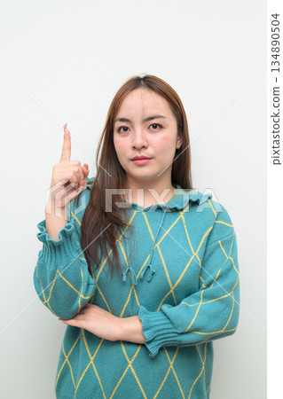 Portrait of a young Asian woman pointing finger against white background 134890504