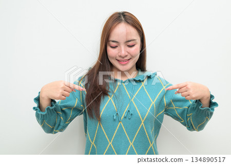 Portrait of a young Asian woman pointing finger against white background Portrait of a young Asian woman pointing finger against white background 134890517
