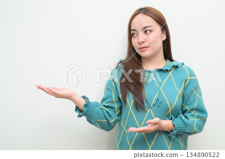Portrait of a young Asian woman against white background showing copy space Portrait of a young Asian woman against white background showing copy space 134890522