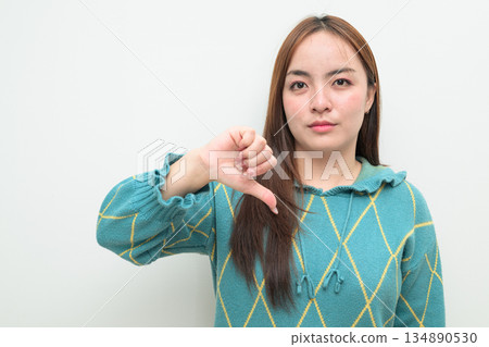 Portrait of a young Asian woman against white background with thumbs down gesture 134890530