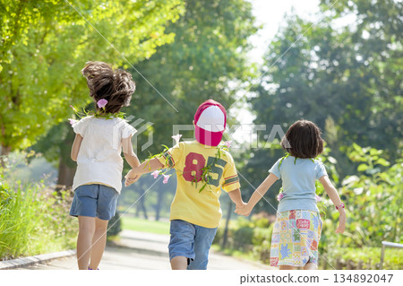 Rear view of three children playing in the park 134892047