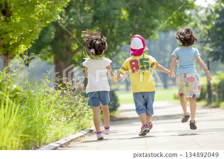 Rear view of three children playing in the park 134892049