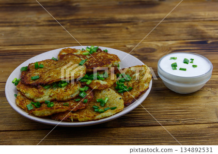 Potato pancakes with sour cream on a wooden table 134892531