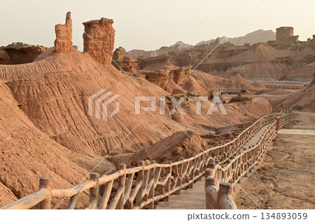 Footpath bridge at Kizil Red Stone Forest Scenic Area in Xinjiang , China is the strangely shaped red rock forests were carved by wind and sand over millions of years. Footpath bridge at Kizil Red Stone Forest Scenic Area in Xinjiang , China is the strangely shaped red rock forests were carved by wind and sand over millions of years. 134893059