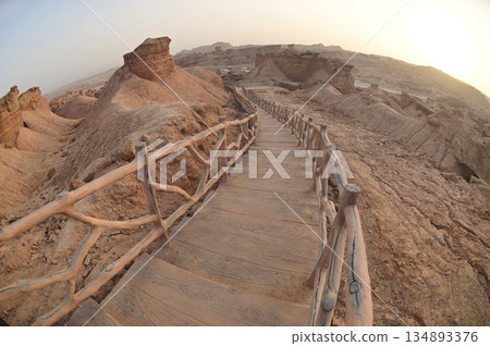 Footpath bridge at Kizil Red Stone Forest Scenic Area in Xinjiang , China is the strangely shaped red rock forests were carved by wind and sand over millions of years. The rocks are red in color. Footpath bridge at Kizil Red Stone Forest Scenic Area in Xinjiang , China is the strangely shaped red rock forests were carved by wind and sand over millions of years. The rocks are red in color. 134893376