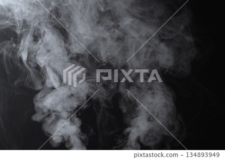 Abstract white smoke and fog drifting on dark black background with ample copy space, atmospheric texture for overlays and design Abstract white smoke and fog drifting on dark black background with ample copy space, atmospheric texture for overlays and design 134893949