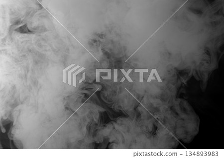Abstract white smoke and fog drifting on dark black background with ample copy space, atmospheric texture for overlays and design Abstract white smoke and fog drifting on dark black background with ample copy space, atmospheric texture for overlays and design 134893983