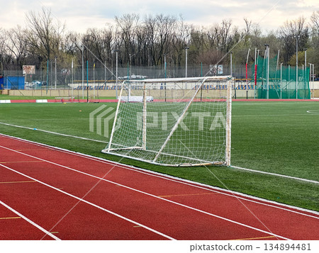 An empty soccer field with goalpost and running track. 134894481