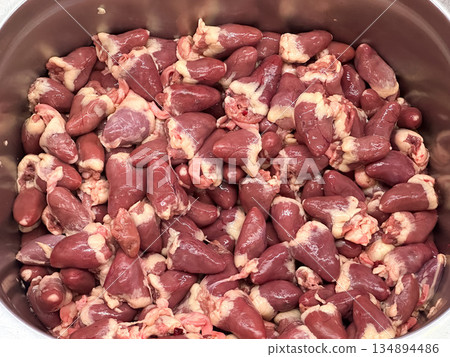 A pile of raw chicken hearts in a metal container. A pile of raw chicken hearts in a metal container. 134894486