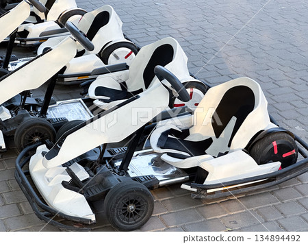 White go-karts lined up on a paved track. 134894492
