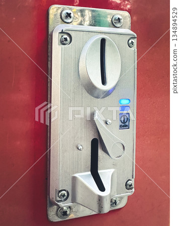 Close-up of a coin slot mechanism on a red vending machine. Close-up of a coin slot mechanism on a red vending machine. 134894529