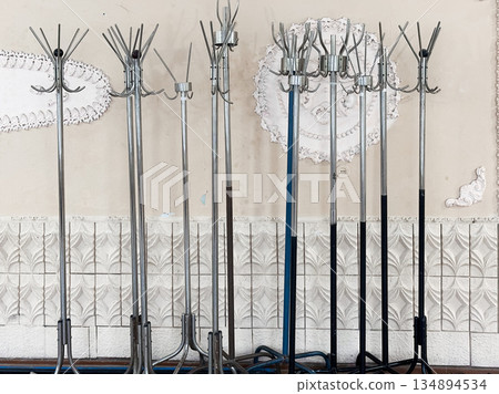 Metal coat racks standing against a decorative wall. Metal coat racks standing against a decorative wall. 134894534