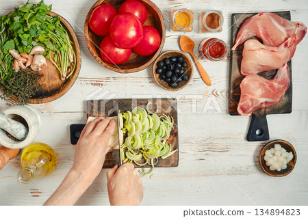 Preparing ingredients for a meal with fresh vegetables, meats, and spices in a kitchen setting 134894823