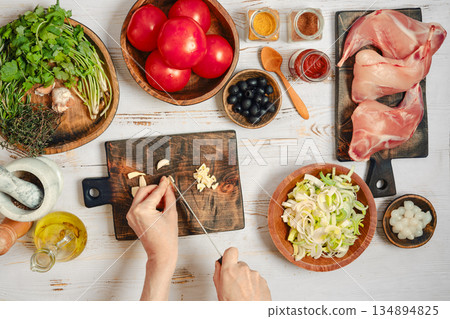 Person is chopping garlic at a kitchen table Person is chopping garlic at a kitchen table 134894825
