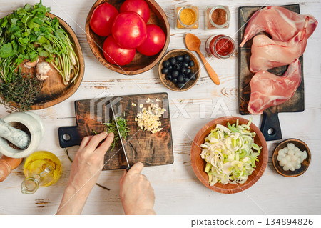 Hands are cutting rosemary on a wooden board Hands are cutting rosemary on a wooden board 134894826