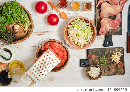 Cooking chicken with fresh ingredients on a wooden table in a kitchen setting during day time Cooking chicken with fresh ingredients on a wooden table in a kitchen setting during day time 134894829