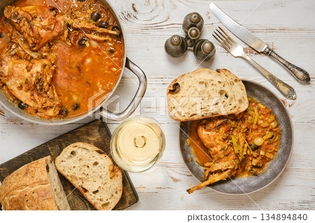 Warm meal with rabbit stew, bread, and white wine on a wooden table 134894840