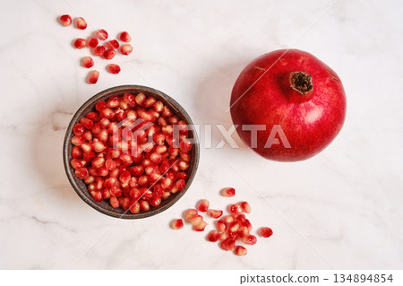 Fresh pomegranate and pomegranate seeds on a marble surface for healthy eating Fresh pomegranate and pomegranate seeds on a marble surface for healthy eating 134894854