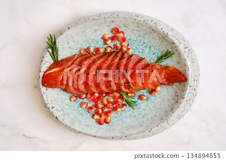 Sliced smoked turkey meat with pomegranate seeds on a plate with fresh herbs Sliced smoked turkey meat with pomegranate seeds on a plate with fresh herbs 134894855