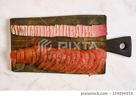 Sliced meat arranged on a wooden cutting board in a kitchen Sliced meat arranged on a wooden cutting board in a kitchen 134894858