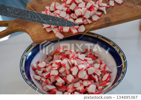 Close Up of Crab Sticks Falling into Bowl from Wooden Board Close Up of Crab Sticks Falling into Bowl from Wooden Board 134895367