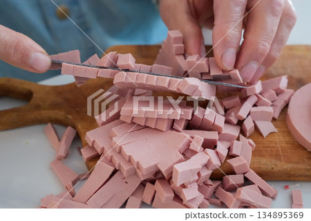 Close Up of Hands Dicing Sausage on Wooden Cutting Board Close Up of Hands Dicing Sausage on Wooden Cutting Board 134895369