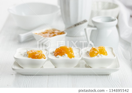 Cottage cheese with cream and mango jam on a white table. Cottage cheese with cream and mango jam on a white table. 134895542