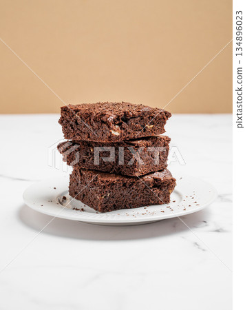 Chocolate brownie on a plate on a marble background close up. Chocolate brownie on a plate on a marble background close up. 134896023